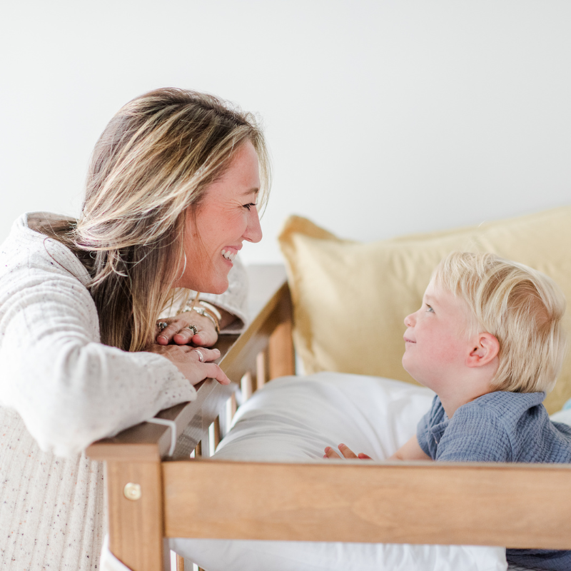 Child in green shirt and orange shorts lying on a textured white surface.