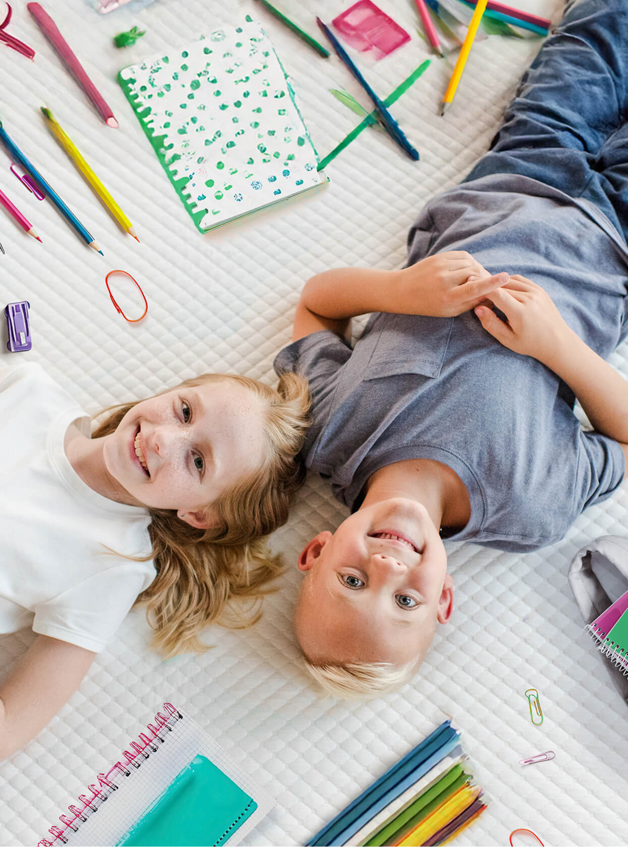 Woman and child lying on a mattress, smiling at one another.