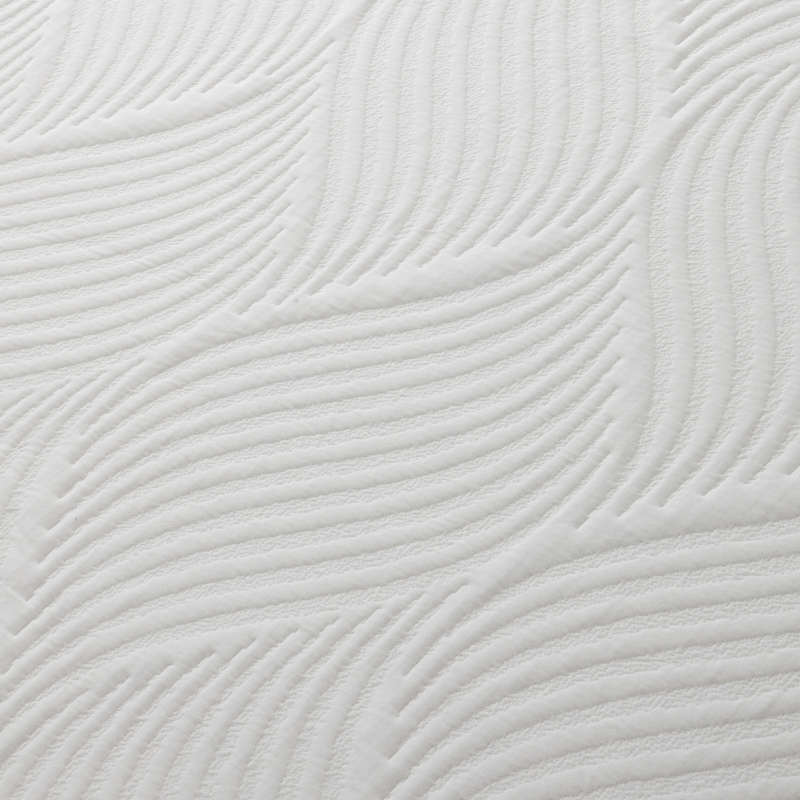 Child in green shirt and orange shorts lying on a textured white surface.