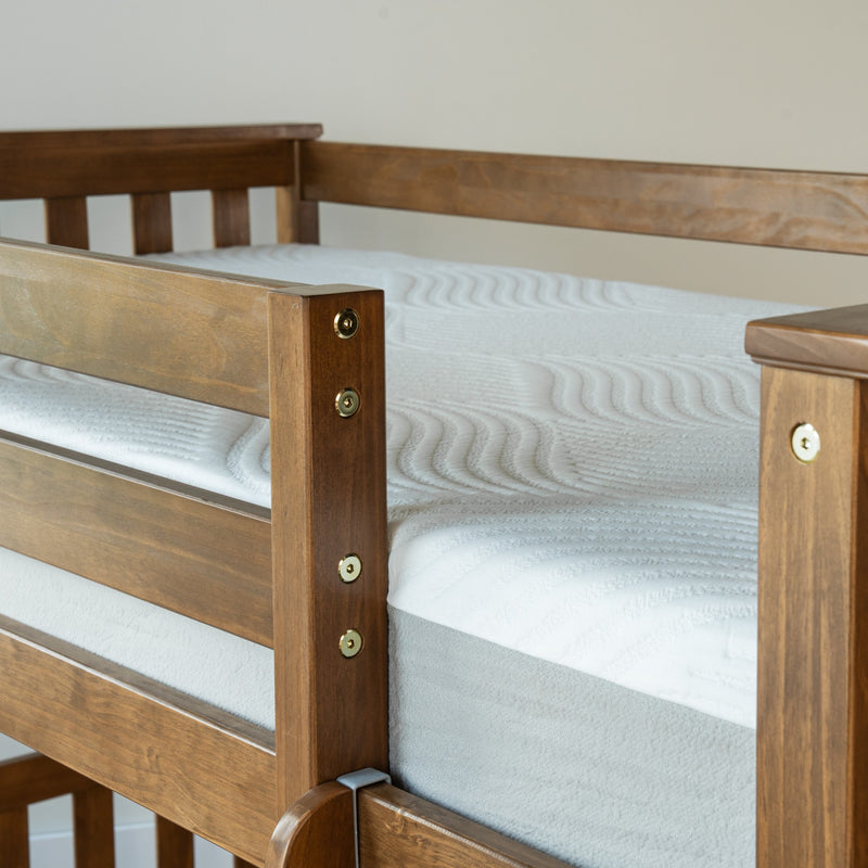 Close-up of wooden bunk bed frame with white textured mattress and brass hardware