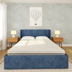 Modern minimalist bedroom with blue upholstered bed frame, white memory foam mattress, wooden nightstands with lamps, and hot air balloon wall art