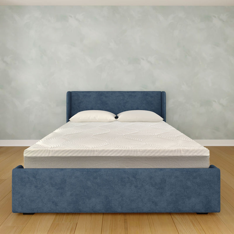 Modern blue upholstered platform bed with white mattress and pillows on hardwood floor against a light textured wall