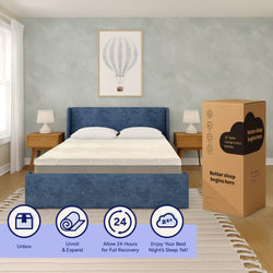 Queen-size cooling memory foam mattress in a box beside a blue upholstered bed in a modern bedroom, unbox and unroll, allow 24 hours for full recovery