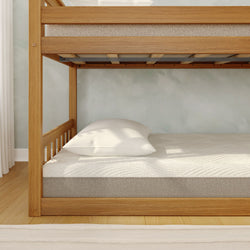 Oak wooden bunk bed lower bunk with white pillow and textured mattress in a minimalist light-filled bedroom