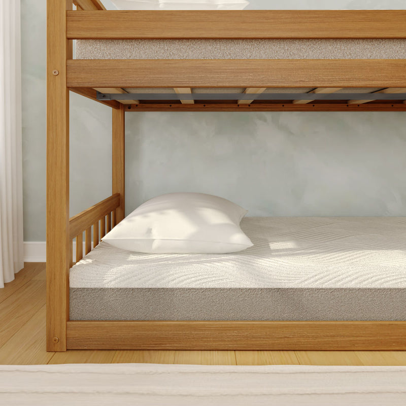 Oak wooden bunk bed lower bunk with white pillow and textured mattress in a minimalist light-filled bedroom
