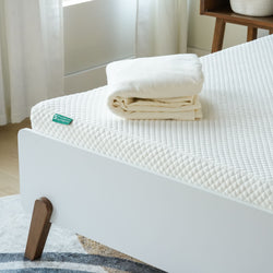 Luxurious white mattress topper with folded cream bedding on modern wooden bed frame.