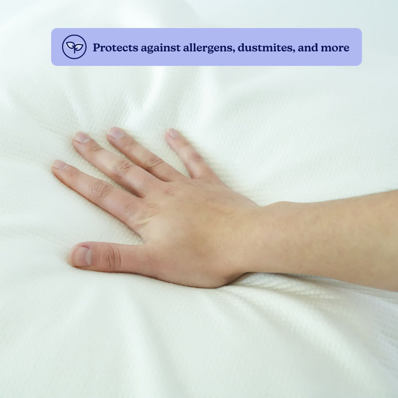 Hand pressing down on a hypoallergenic pillow surface, showcasing its protection against allergens and dust mites.