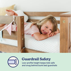 Child smiling on a safe bunk bed with guardrail, emphasizing guardrail safety for kids.