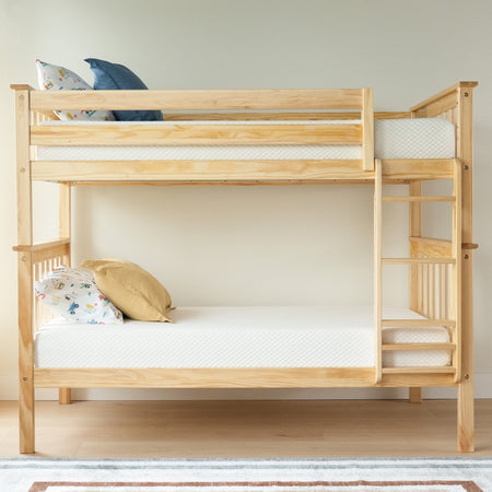 Light wood bunk bed with white mattresses and colorful pillows in a minimalist bedroom setting.